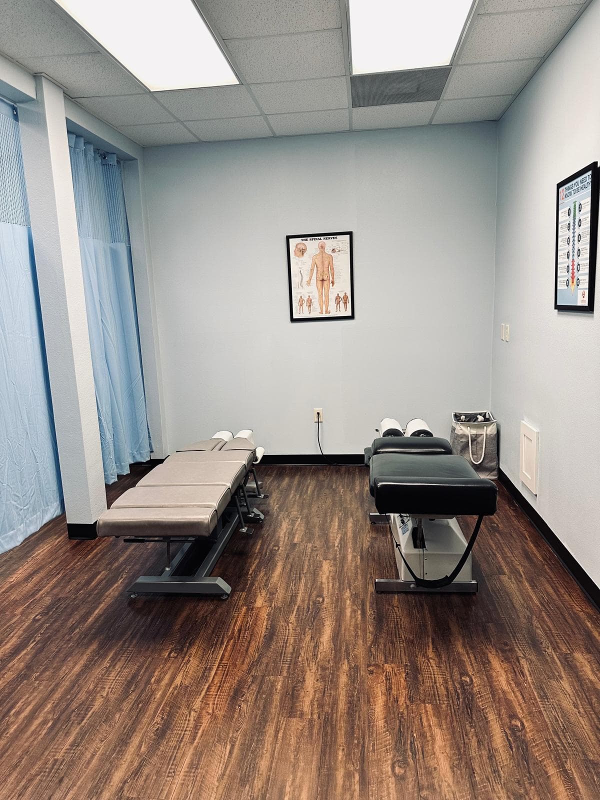 Quiet upper cervical care treatment room at Atlas Injury to Health with two adjustable tables and a spinal nerve chart