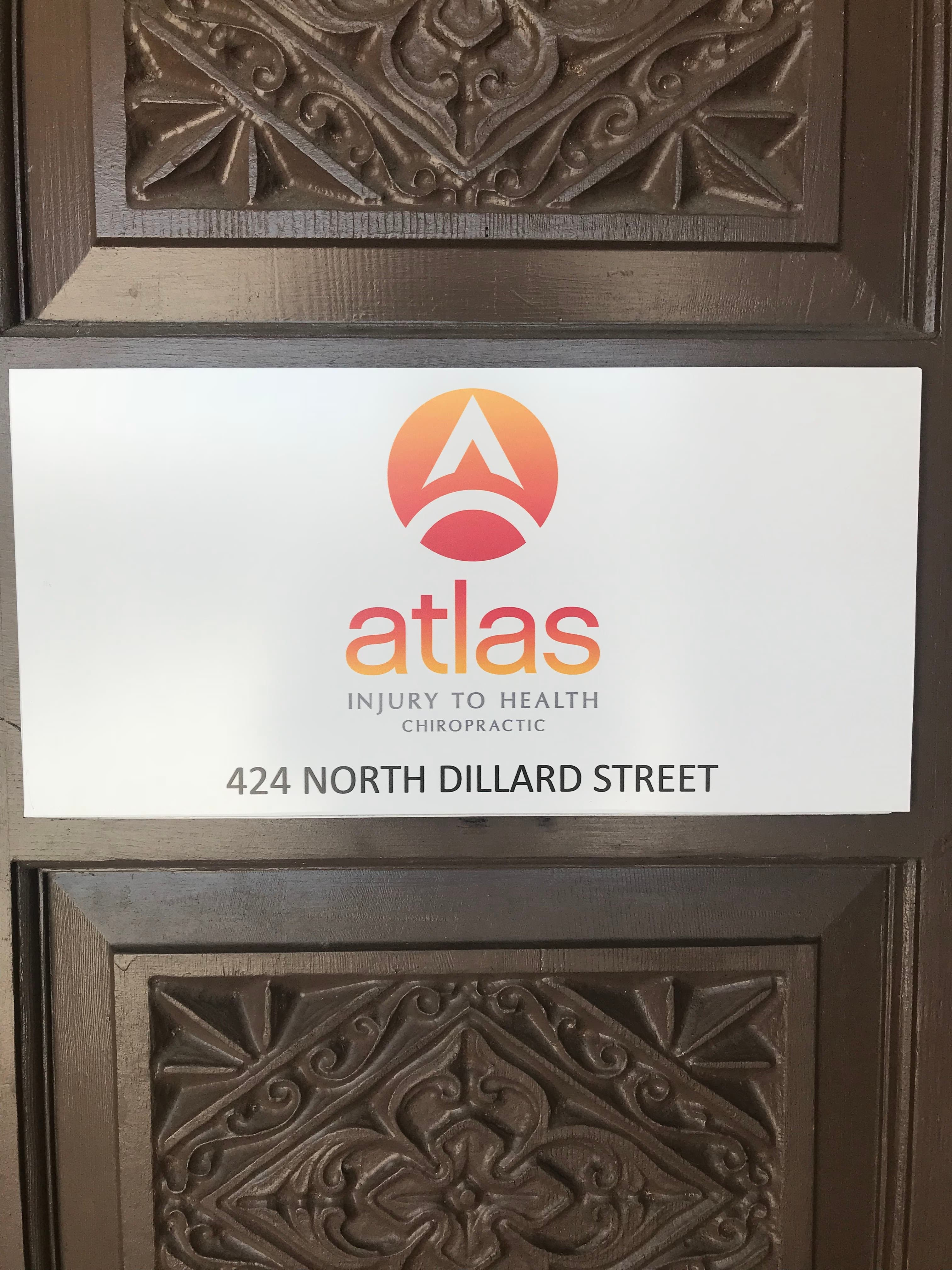 Atlas Injury to Health Chiropractic entrance sign at 424 North Dillard Street, mounted on a carved wooden door